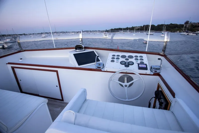 Slide: The Image of Helm of 1964 Huckins Out Islander 56 yacht with scenic harbor view. - 22