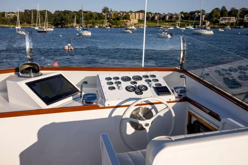 Slide: The Image of Helm of 1964 Huckins Out Islander 56 yacht with scenic harbor view. - 23