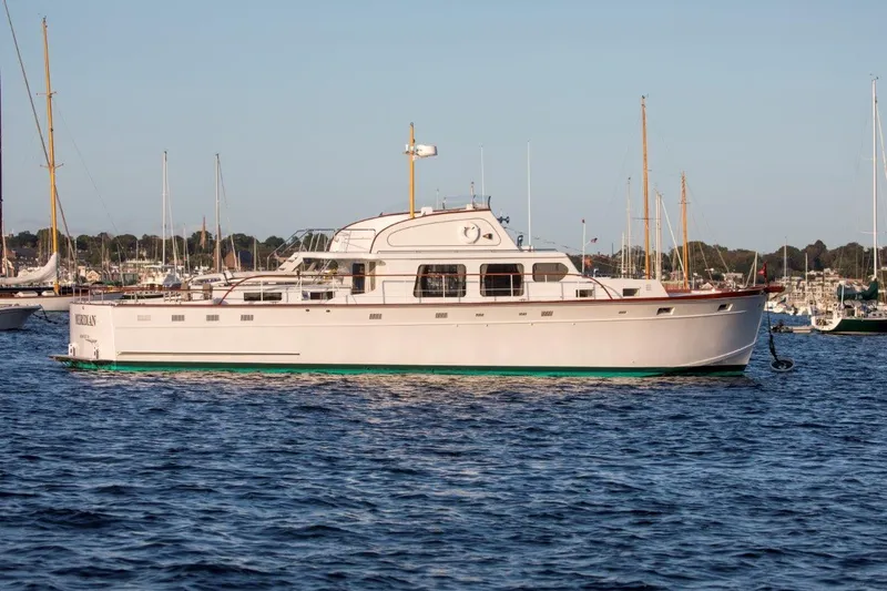 Slide: The Image of 1964 Huckins Out Islander 56 yacht on calm water, with marina background. - 25