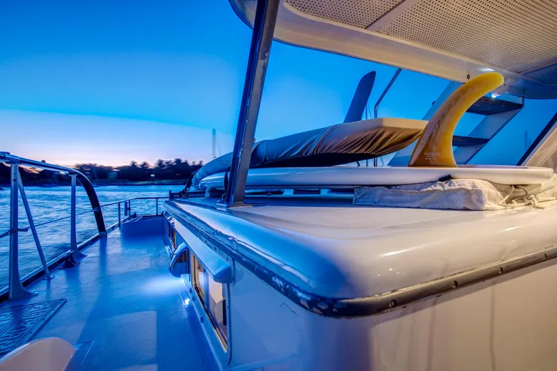 Slide: The Image of 1964 Huckins Out Islander 56 yacht deck at sunset, featuring sleek design and surfboard storage. - 30