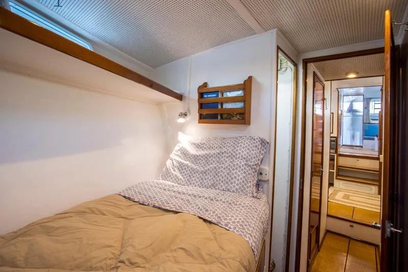 Slide: The Image of Cozy cabin interior of 1964 Huckins Out Islander 56 yacht with bed and wooden accents. - 40