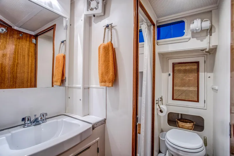 Slide: The Image of 1964 Huckins Out Islander 56 yacht bathroom with sink, toilet, and orange towels. - 44