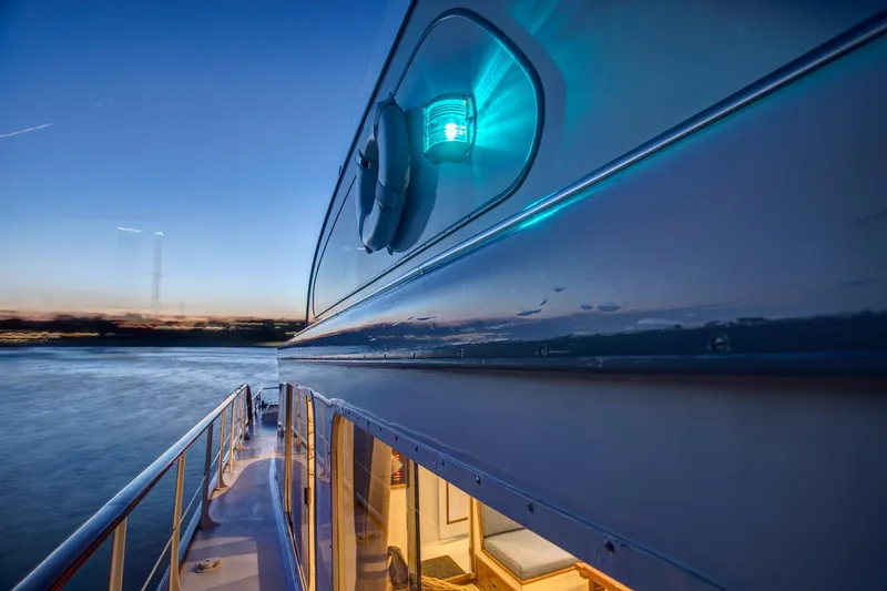 Slide: The Image of 1964 Huckins Out Islander 56 yacht at sunset, showcasing sleek design and illuminated interior. - 47