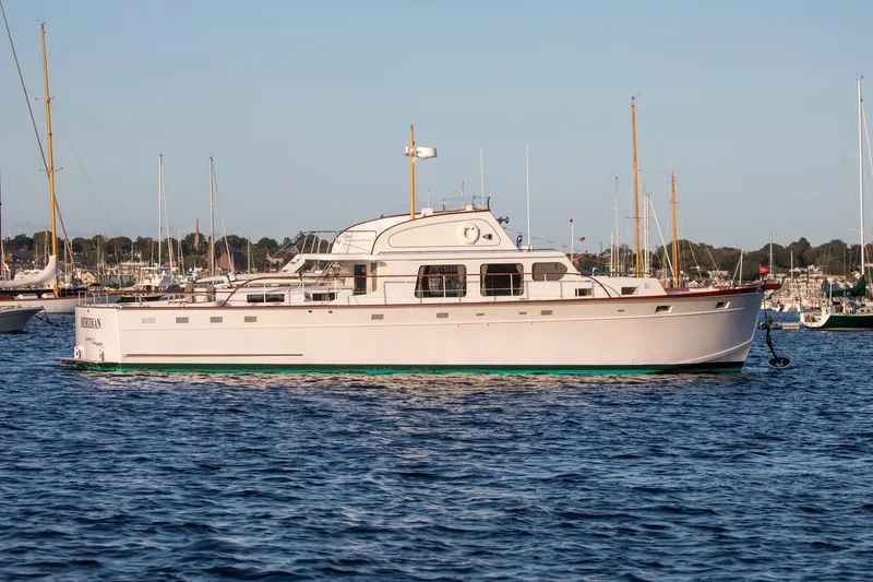 Slide: The Image of 1964 Huckins Out Islander 56 yacht on calm water, surrounded by sailboats. - 49