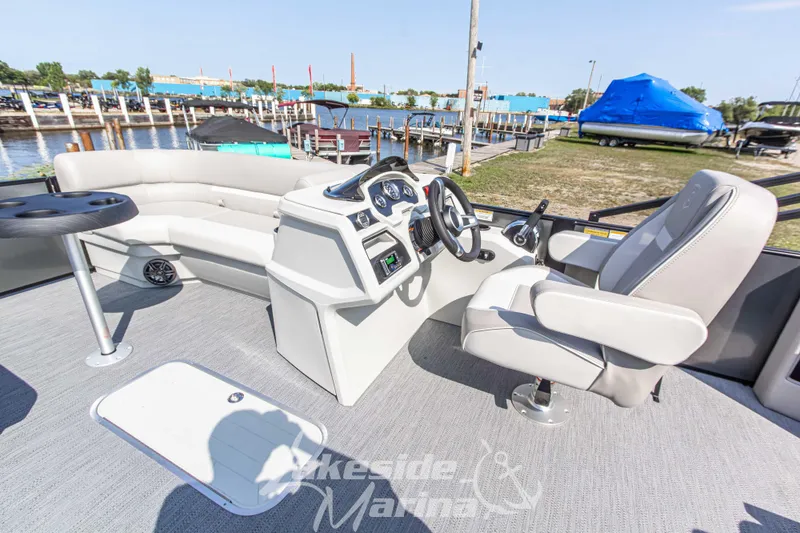 Slide: The Image of 2026 Godfrey Sweetwater 2286 SFLX boat interior with helm, seating, and table at marina. - 15
