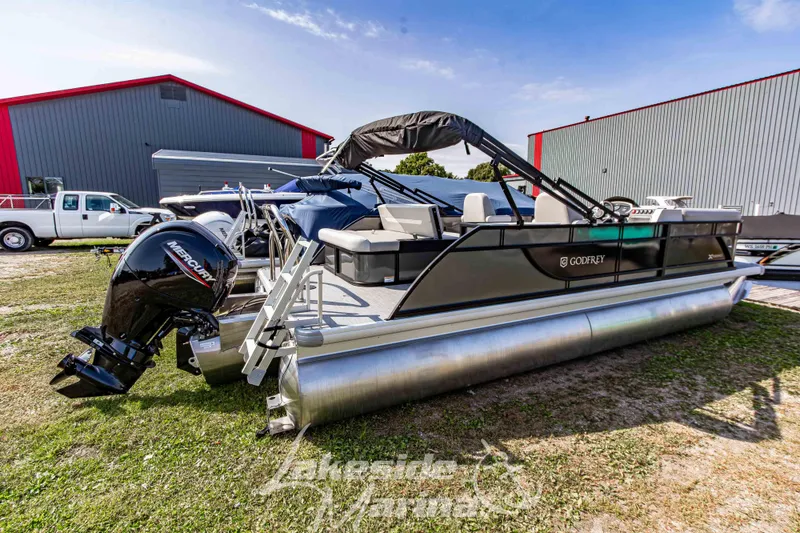 Slide: The Image of 2026 Godfrey Sweetwater 2286 SFLX pontoon boat with Mercury engine, parked outdoors. - 5