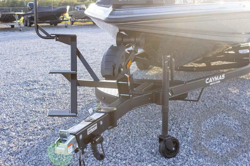 Slide: The Image of 2026 Caymas CX 21 PRO boat trailer on gravel lot, featuring sturdy hitch and wheel. - 19