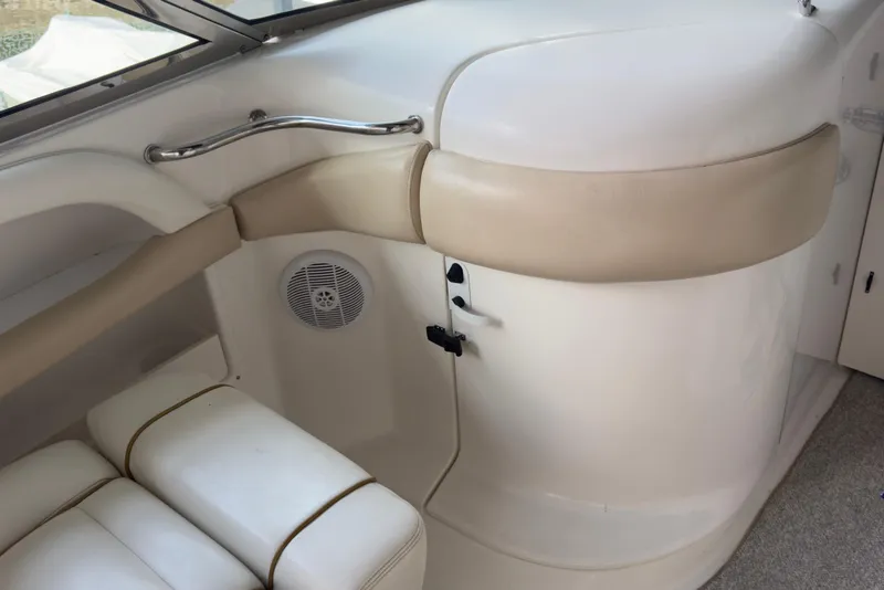Slide: The Image of 2003 Sea Ray 290 Bowrider interior with beige and white seating, speaker, and handle. - 13