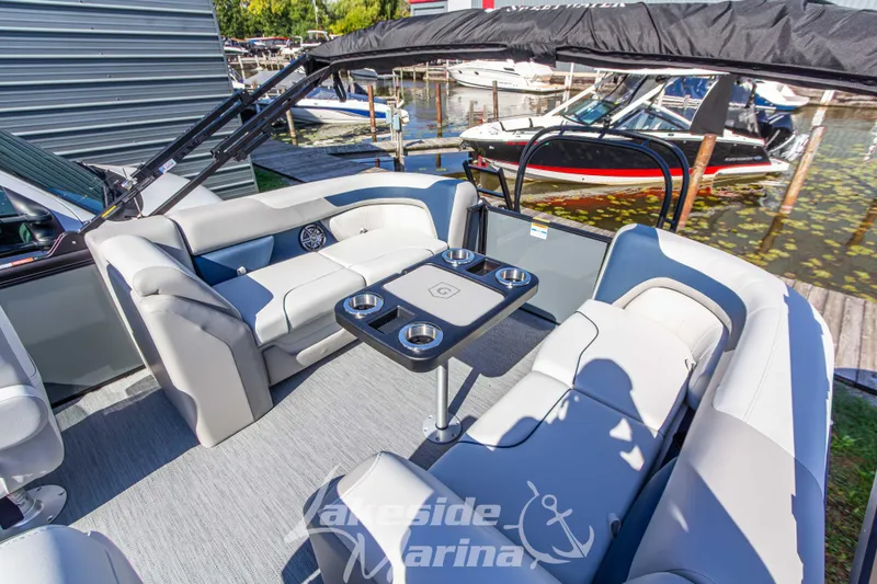 Slide: The Image of 2026 Godfrey Sweetwater 2286 SB pontoon boat interior with seating and table at marina. - 20
