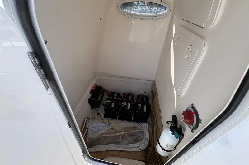 Slide: The Image of 2020 Pioneer 222 Sportfish storage compartment with batteries and fire extinguisher. - 23