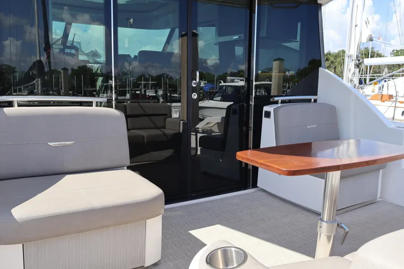 Slide: The Image of 2020 Tiara Yachts C44 Coupe cockpit with seating and wooden table, docked at marina. - 18