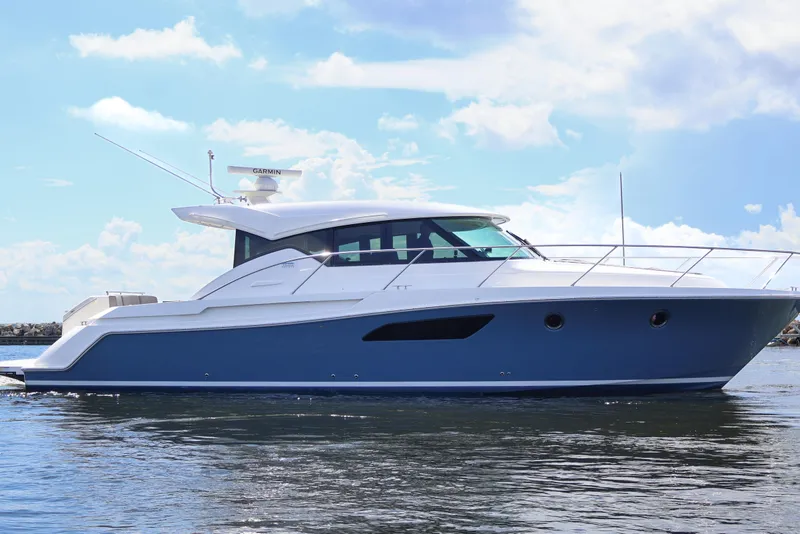Slide: The Image of 2020 Tiara Yachts C44 Coupe cruising on calm waters under a clear sky. - 2