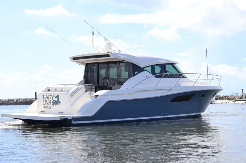Slide: The Image of 2020 Tiara Yachts C44 Coupe cruising on water, clear sky background. - 7