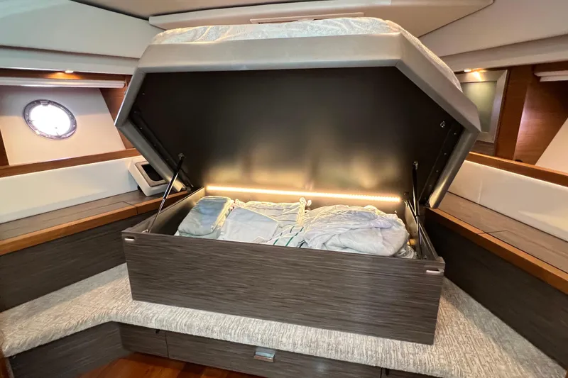 Slide: The Image of 2020 Tiara Yachts C44 Coupe interior with open storage compartment and bedding. - 77