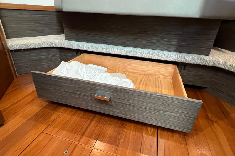 Slide: The Image of Open storage drawer in 2020 Tiara Yachts C44 Coupe, featuring wood finish and bedding. - 79