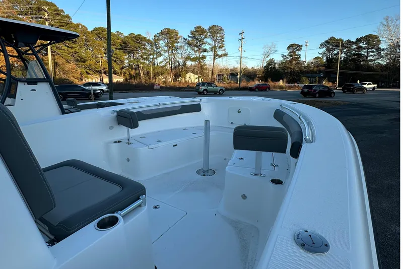 Slide: The Image of 2024 Sea Born LX 26 LE boat interior with seating and cup holders, parked outdoors. - 13