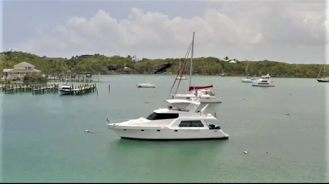 Slide: The Image of 2007 Pama 540 LX Pilothouse yacht anchored in a serene bay with other boats. - 14