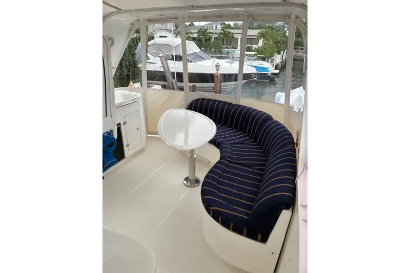 Slide: The Image of 2007 Pama 540 LX Pilothouse interior with curved seating and table, docked near other boats. - 16