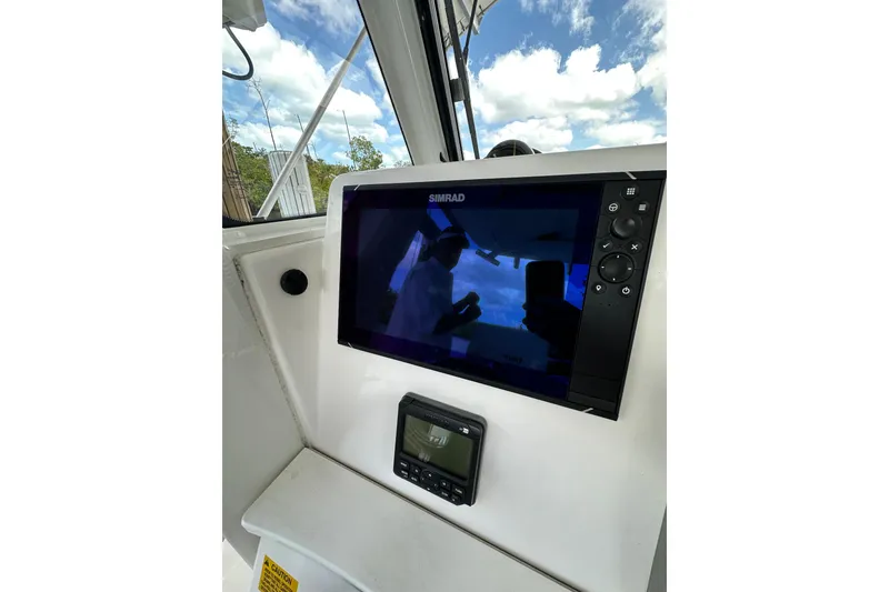Slide: The Image of 2015 Everglades 295 Center Console boat dashboard with Simrad display and clear sky reflection. - 23