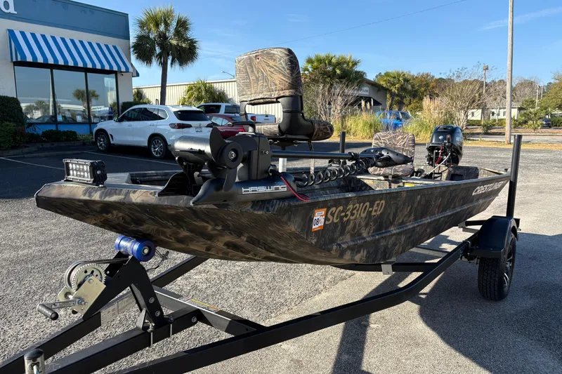 Slide: The Image of 2022 Crestliner 1546 Retriever boat on trailer, parked outdoors, camo design. - 13