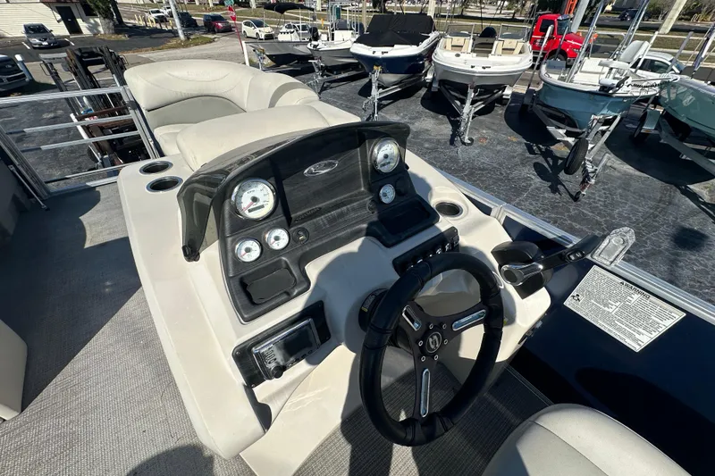 Slide: The Image of 2018 Sylvan Mirage Cruise 8520 dashboard with steering wheel and gauges, parked among other boats. - 14