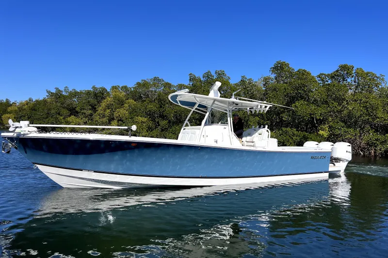 The Image of 2018 Regulator 34 Center Console boat on calm water, surrounded by lush greenery. - 0