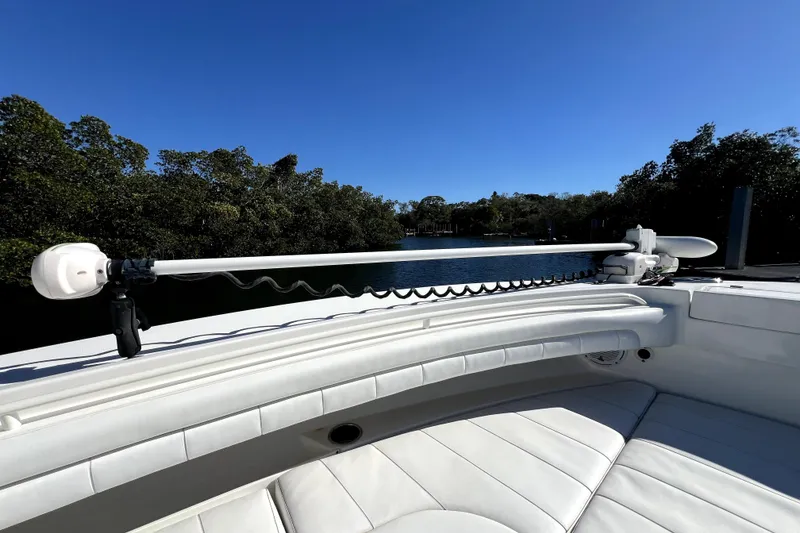 Slide: The Image of 2018 Regulator 34 Center Console boat with white seating and trolling motor, near water. - 14