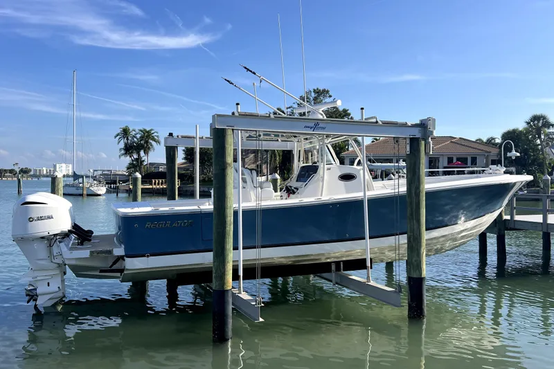 Slide: The Image of 2018 Regulator 34 Center Console boat cruising on clear water, surrounded by lush greenery. - 2