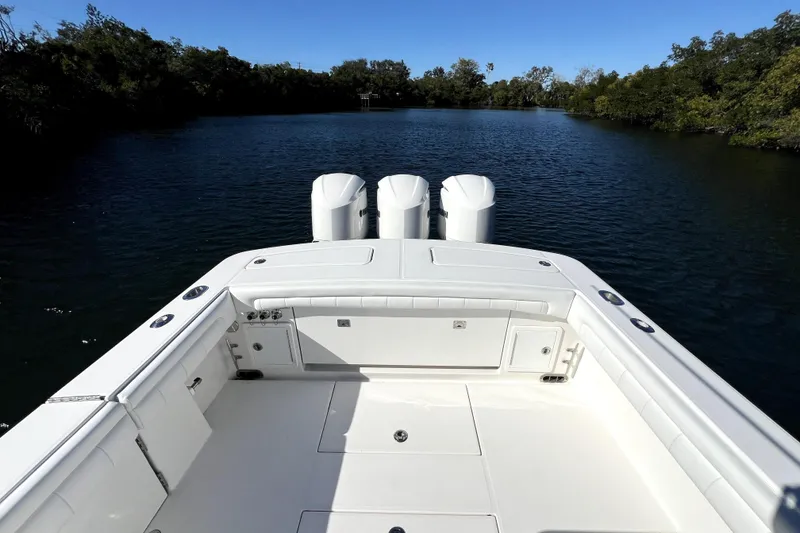 Slide: The Image of 2018 Regulator 34 Center Console boat on calm water, featuring triple outboard engines. - 36