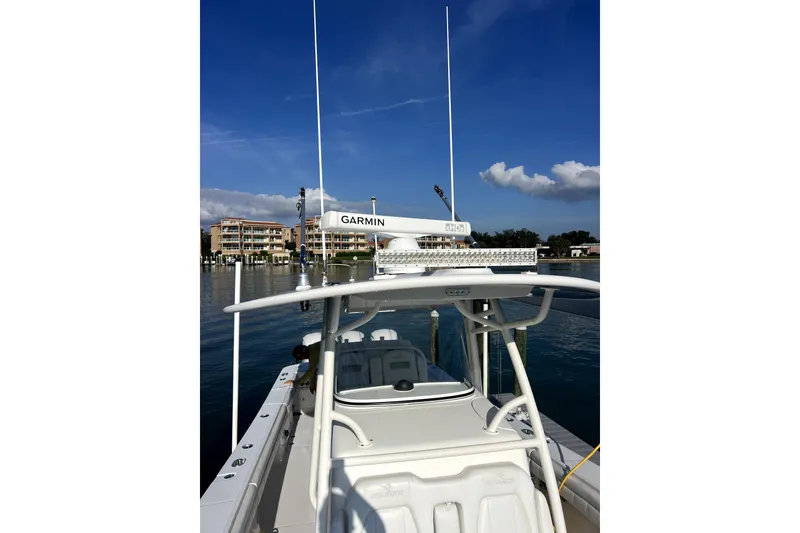 Slide: The Image of 2018 Regulator 34 Center Console boat cruising on a sunny day with lush greenery. - 4
