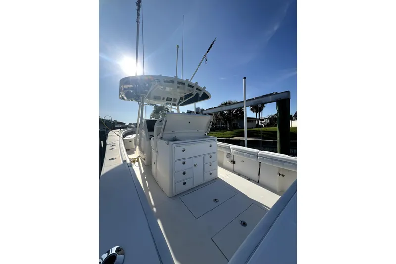 Slide: The Image of 2018 Regulator 34 Center Console boat with spacious seating, docked near lush greenery. - 8
