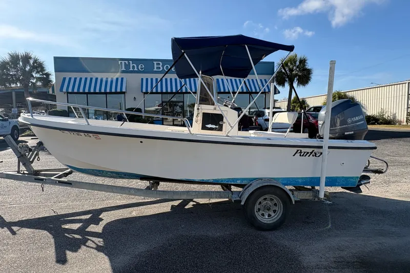 The Image of 1992 Parker 18 boat on trailer, parked outside a store with blue-striped awnings. - 1