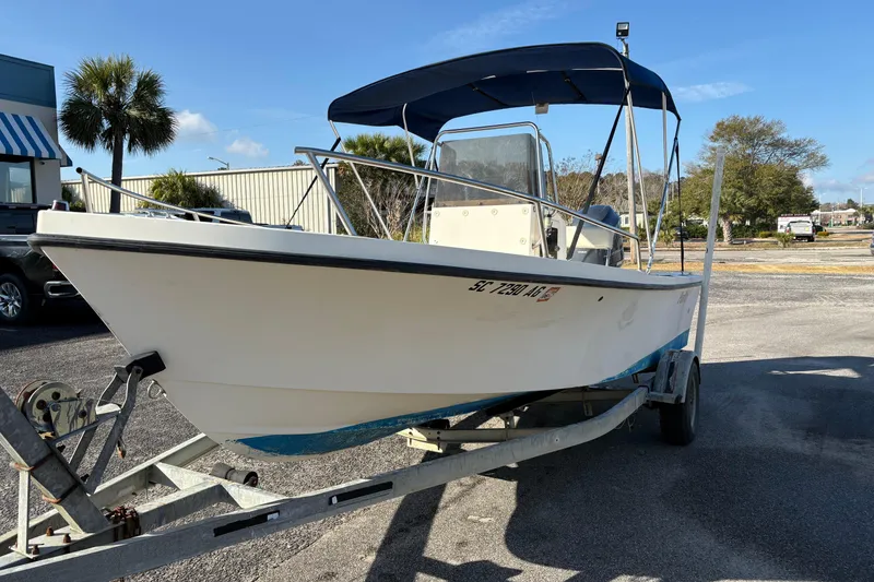 Slide: The Image of 1992 Parker 18 boat on trailer with blue canopy, parked outdoors under clear sky. - 8