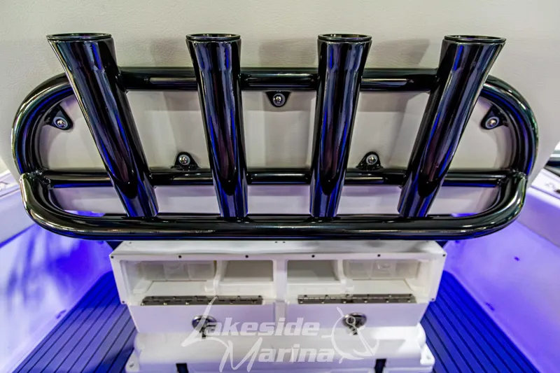 Slide: The Image of 2026 Tidewater 232 LXF boat interior with rod holders and storage, illuminated in blue lighting. - 15