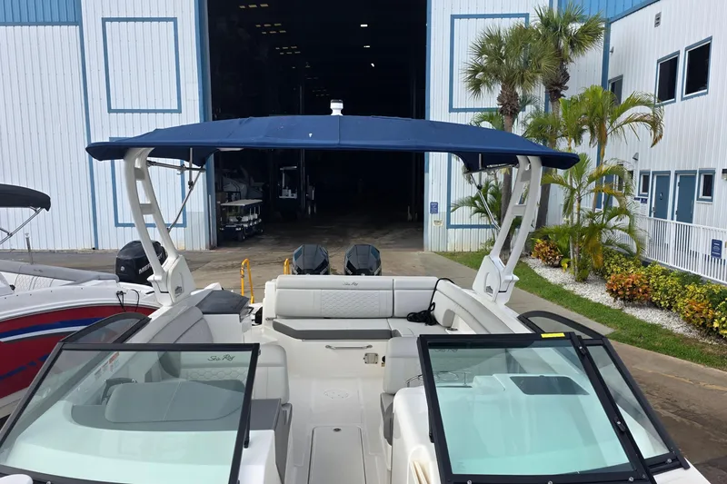 Slide: The Image of 2021 Sea Ray SDX 290 Outboard boat with blue canopy, docked near a warehouse. - 24