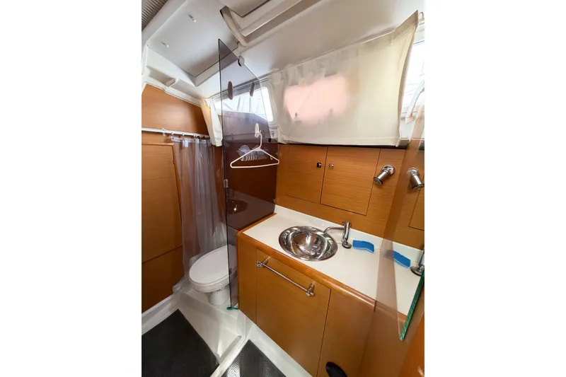 Slide: The Image of 2013 Jeanneau Sun Odyssey 409 yacht bathroom with sink, toilet, and wooden cabinetry. - 62
