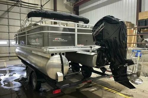 Slide: The Image of 2024 Sun Tracker Fishin' Barge 20 DLX pontoon boat with Mercury outboard motor in a garage. - 4