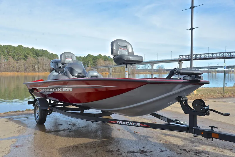 Slide: The Image of 2023 Tracker Pro Team 175 TXW boat on trailer by a lake with bridge background. - 16