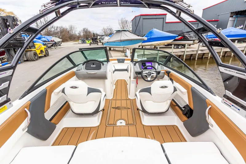 Slide: The Image of 2025 Chaparral 21 SSi boat interior with modern dashboard and seating at a marina. - 13
