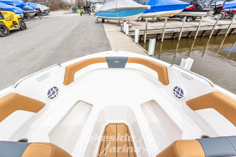 Slide: The Image of 2025 Chaparral 21 SSi boat interior with tan and white seating at a marina. - 30