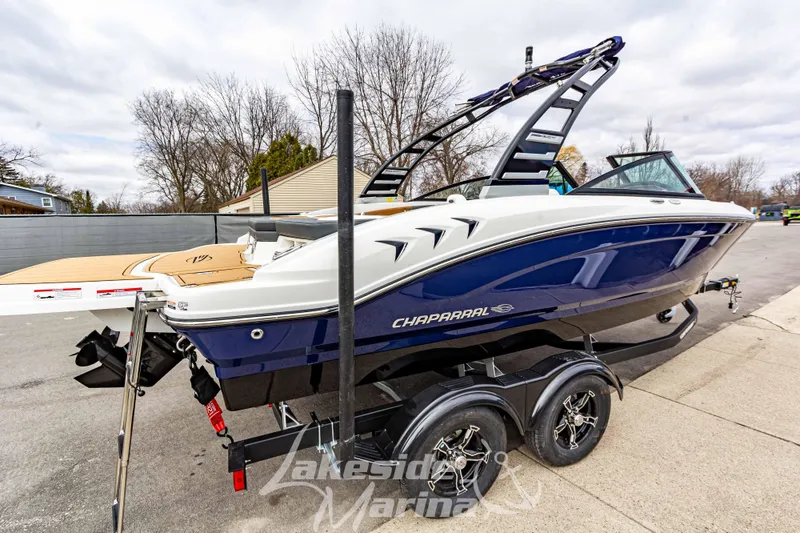 Slide: The Image of 2025 Chaparral 21 SSi boat on trailer, blue and white design, parked outdoors. - 7