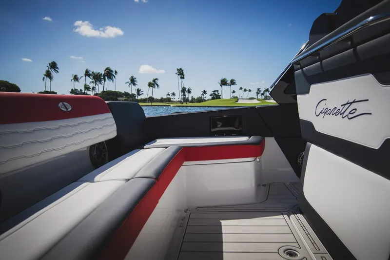 Slide: The Image of 2025 Cigarette 41 Nighthawk boat interior with red and white seating, palm trees in background. - 36