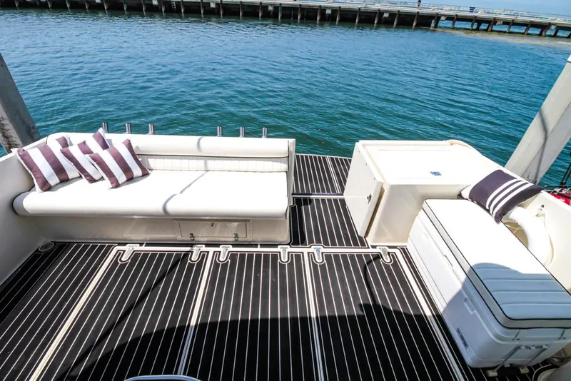 Slide: The Image of 1988 Californian Veneti boat deck with white seating and striped cushions, overlooking calm water. - 35