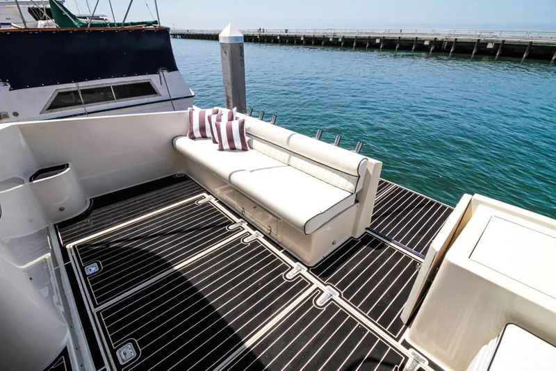 Slide: The Image of 1988 Californian Veneti yacht deck with white seating and striped pillows by the water. - 37