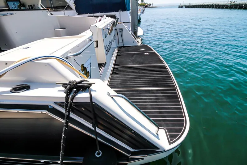 Slide: The Image of 1988 Californian Veneti boat docked, featuring a sleek black deck and calm water backdrop. - 39