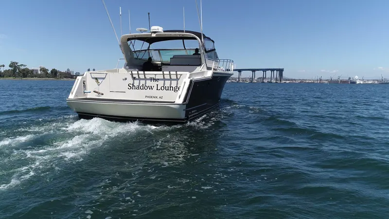 Slide: The Image of 1988 Californian Veneti boat "Shadow Lounge" cruising on open water with bridge in background. - 5