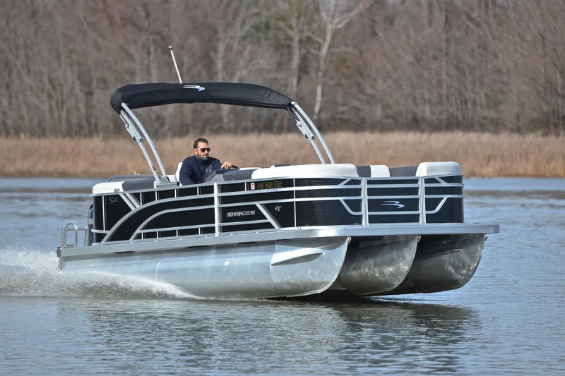The Image of 2025 Bennington 22 S pontoon boat cruising on a calm lake. - 1