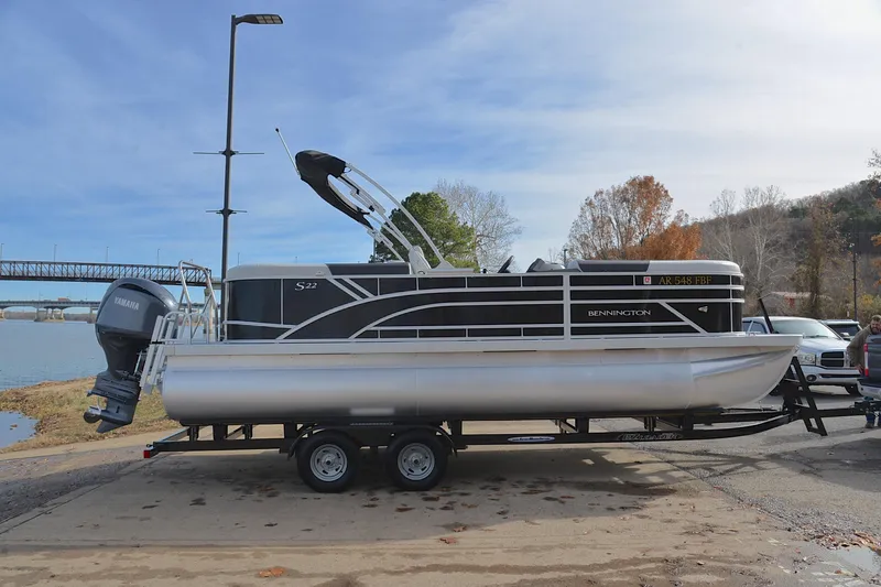 Slide: The Image of 2025 Bennington 22 S pontoon boat on trailer by riverside, featuring Yamaha outboard motor. - 15