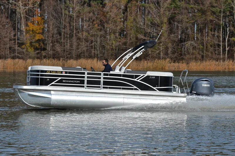 Slide: The Image of 2025 Bennington 22 S pontoon boat cruising on a lake with Yamaha outboard motor. - 2