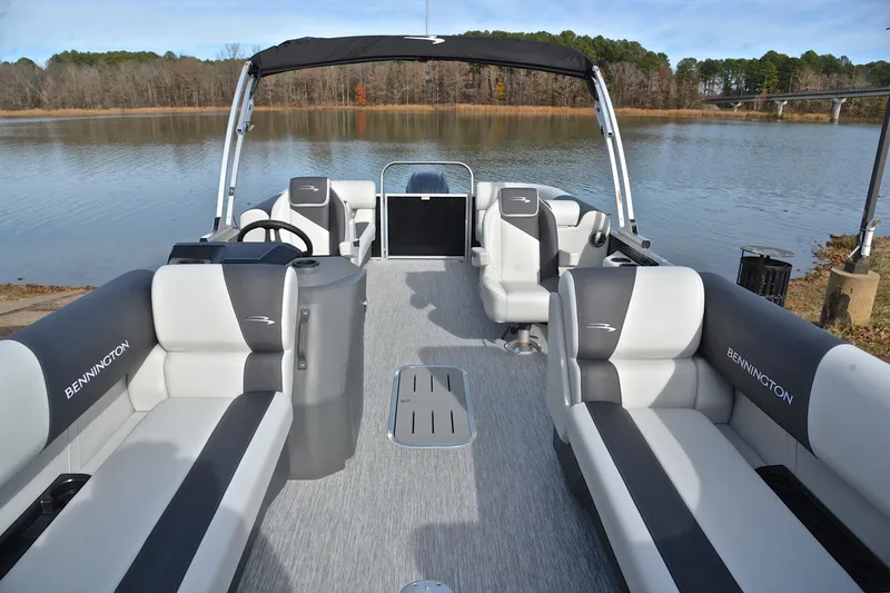 Slide: The Image of 2025 Bennington 22 S pontoon boat with sleek seating, docked by a serene lake. - 20